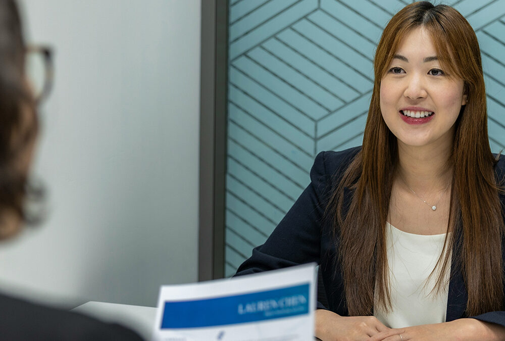 A hiring manager interviewing a candidate while reviewing her resume